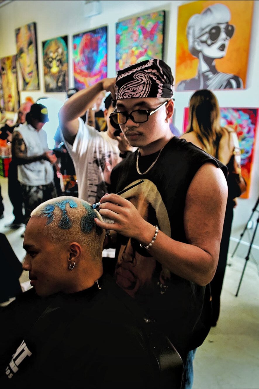 Artist hand-painting a blue design into a buzz cut at a fyf North event